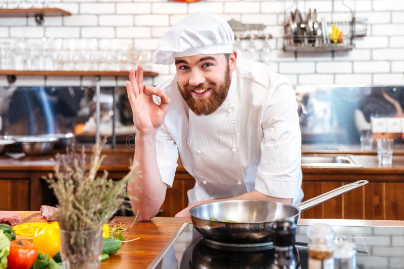 Vrolijke gebaarde chef-kokkok die en o.k. teken koken tonen royalty-vrije stock afbeeldingen Vrolijke gebaarde chef-kokkok die en o.k. teken koken tonen royalty-vrije stock afbeeldingen