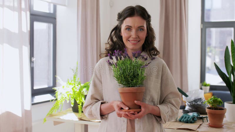 Vrolijke glimlachende vrouw houdt potbloem thuis vast