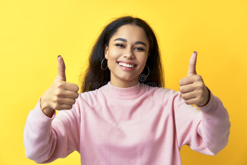 Happy smiling black woman showing thumbs up on yellow background. Motivation, ok, success concept. Happy smiling black woman showing thumbs up on yellow background. Motivation, ok, success concept.