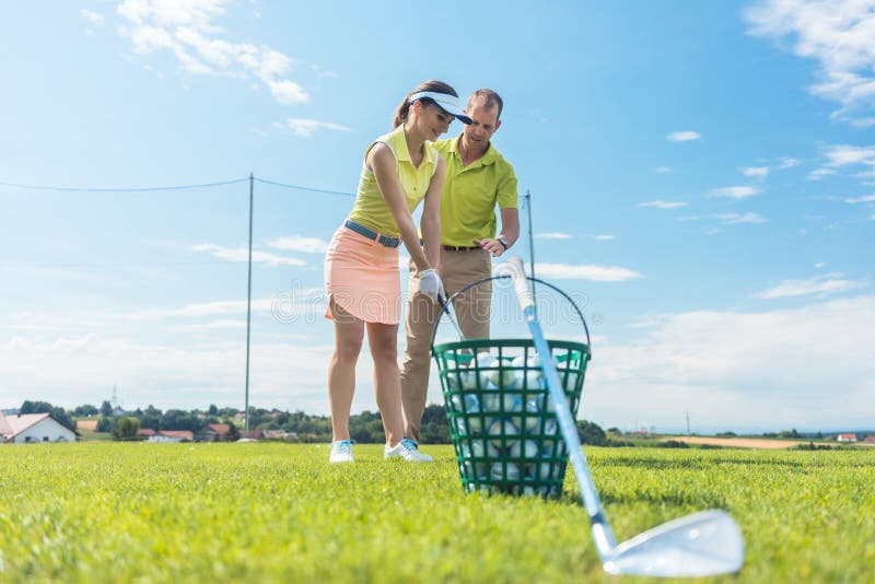 Vrolijke jonge vrouw die de correcte greep en de beweging voor het gebruiken van de golfclub leren stock afbeelding Vrolijke jonge vrouw die de correcte greep en de beweging voor het gebruiken van de golfclub leren stock afbeelding