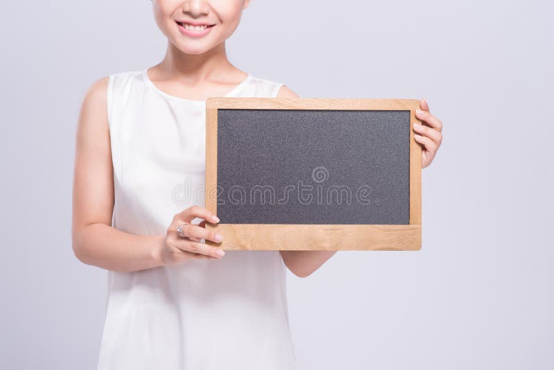 Vrolijke jonge vrouw in het witte teken van de hemdsholding over grijze bac stock foto's Vrolijke jonge vrouw in het witte teken van de hemdsholding over grijze bac stock foto's