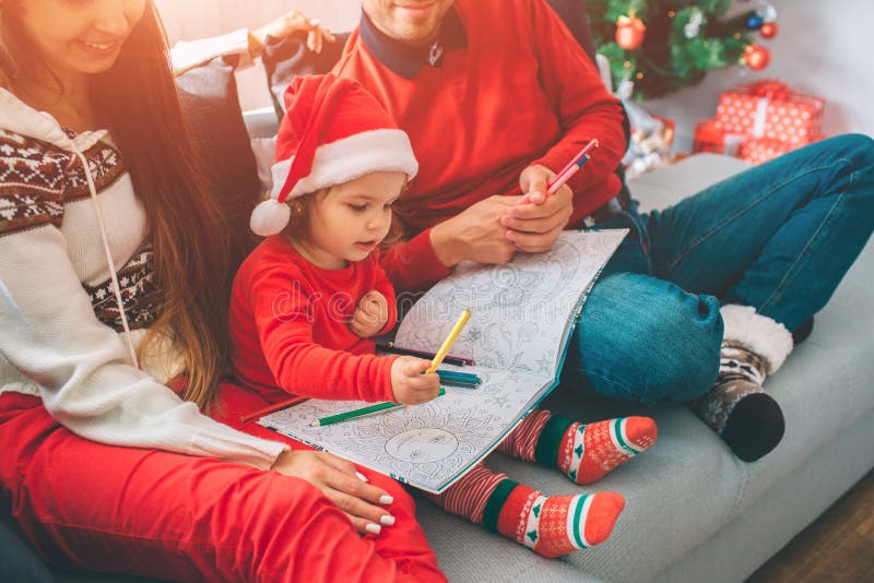 Vrolijke Kerstmis en Gelukkig Nieuwjaar Besnoeiingsmening van ouders die op bank met hun kind zitten Het jonge geitje houdt kleur stock foto Vrolijke Kerstmis en Gelukkig Nieuwjaar Besnoeiingsmening van ouders die op bank met hun kind zitten Het jonge geitje houdt kleur stock foto