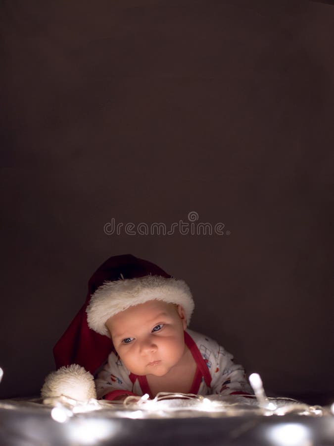 Vrolijke Kerstmis en Gelukkig Nieuwjaar Pasgeboren baby met Kerstmanhoed die op Kerstmislichten liggen Luchtruimte voor tekst of royalty-vrije stock foto's Vrolijke Kerstmis en Gelukkig Nieuwjaar Pasgeboren baby met Kerstmanhoed die op Kerstmislichten liggen Luchtruimte voor tekst of royalty-vrije stock foto's