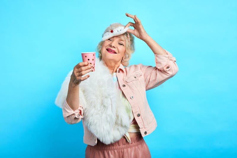 Vrolijke oude vrouw die beschikbare plasic kop van T-stuk houden stock fotografie Vrolijke oude vrouw die beschikbare plasic kop van T-stuk houden stock fotografie