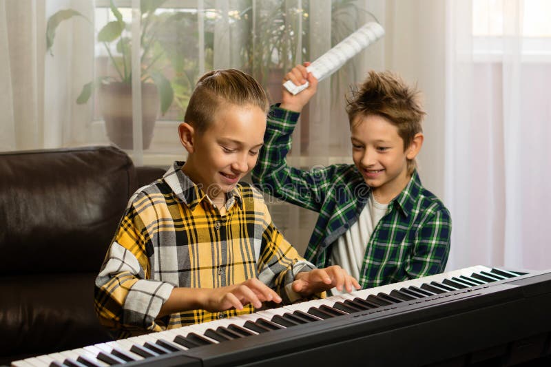 Two playful boys sharing a fun moment during piano practice in a bright room. Two playful boys sharing a fun moment during piano practice in a bright room