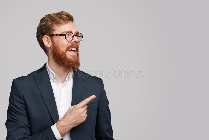 Vrolijke rode haired zakenman die op exemplaarruimte richten stock afbeeldingen Vrolijke rode haired zakenman die op exemplaarruimte richten stock afbeeldingen