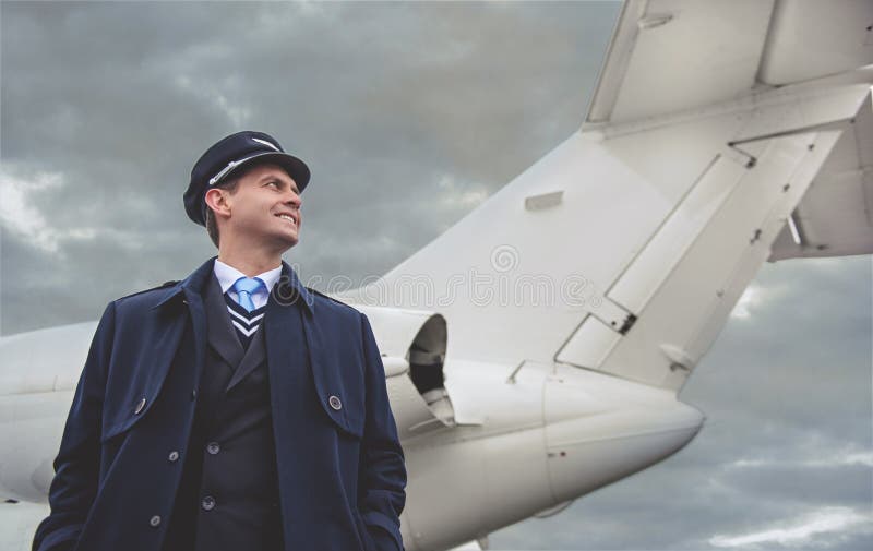 Vrolijke vliegenier die dichtbij vliegtuigen situeren stock afbeeldingen Vrolijke vliegenier die dichtbij vliegtuigen situeren stock afbeeldingen