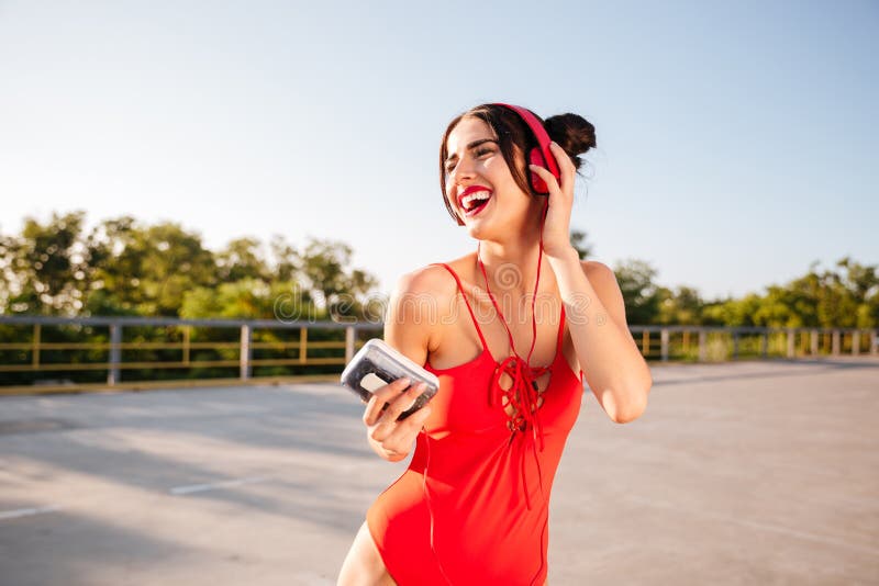 Vrolijke vrouw die in zwempak aan muziek en het lachen luisteren stock fotografie Vrolijke vrouw die in zwempak aan muziek en het lachen luisteren stock fotografie