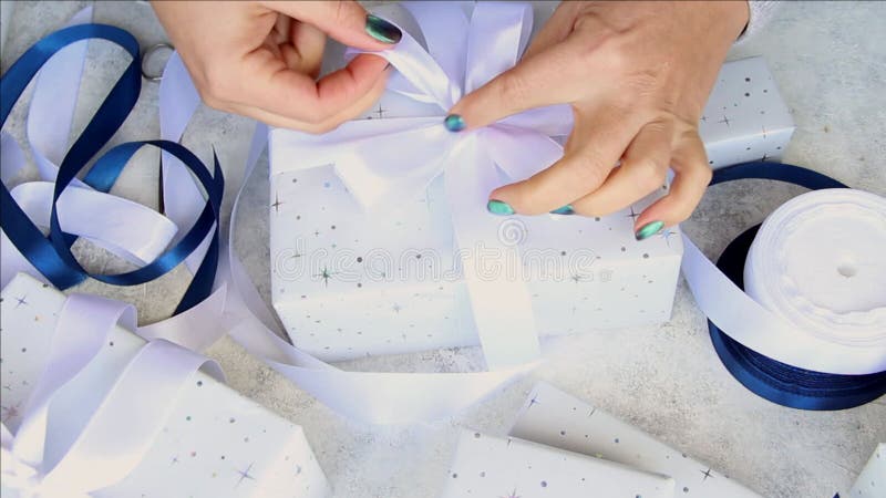 Vrouw bindt een lintboeg op een omhuld cadeau stock video