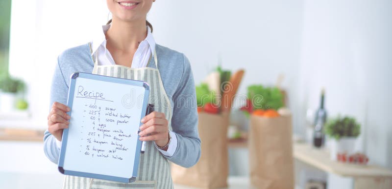 Vrouw in de keuken die thuis, zich dichtbij bureau met omslag bevinden stock fotografie Vrouw in de keuken die thuis, zich dichtbij bureau met omslag bevinden stock fotografie