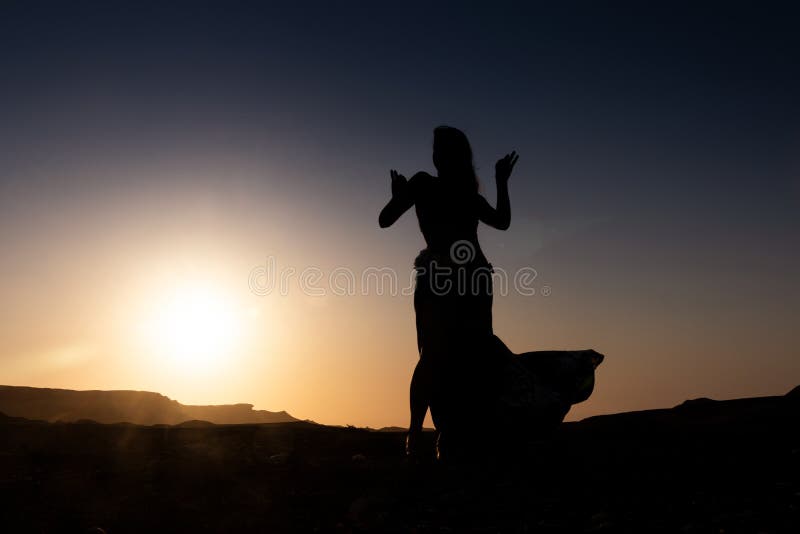 Vrouw die aan de beroemde Arabische buikdans dansen Met zonsondergang in de dorre woestijnvlakte van Namibe afrika angola royalty-vrije stock fotografie Vrouw die aan de beroemde Arabische buikdans dansen Met zonsondergang in de dorre woestijnvlakte van Namibe afrika angola royalty-vrije stock fotografie