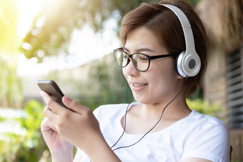 Vrouw die aan de muziek met hoofdtelefoon en slimme telefoon luisteren stock foto Vrouw die aan de muziek met hoofdtelefoon en slimme telefoon luisteren stock foto