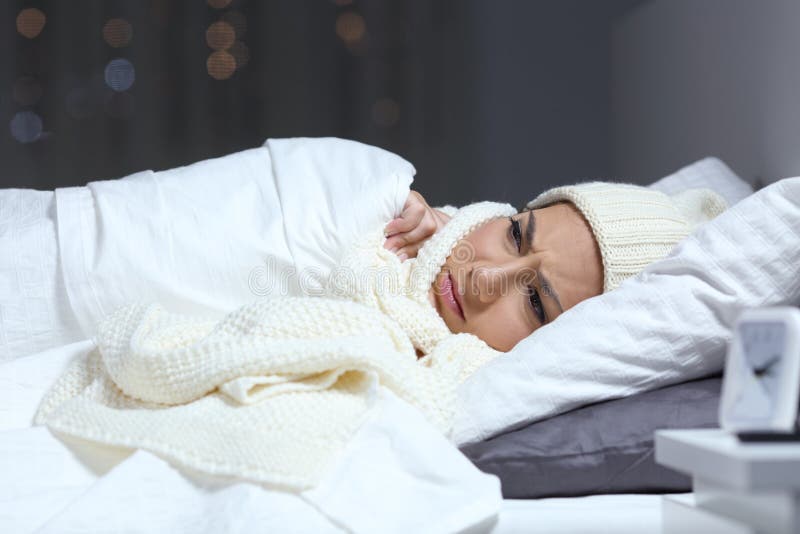 Vrouw die aan koude in een bed in de winter lijden