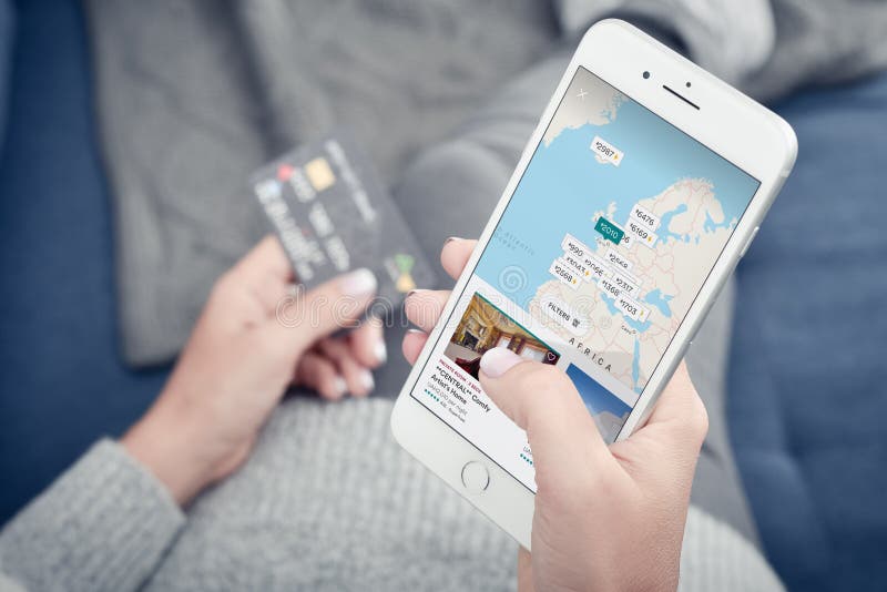 Vrouw die de Airbnb-app gebruikt op een Apple iPhone 8 Plus stock afbeelding