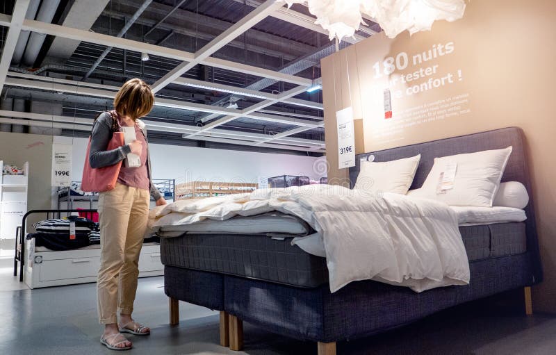 Vrouw die beddekbed bekijken die bedlinnen kiezen stock foto Vrouw die beddekbed bekijken die bedlinnen kiezen stock foto