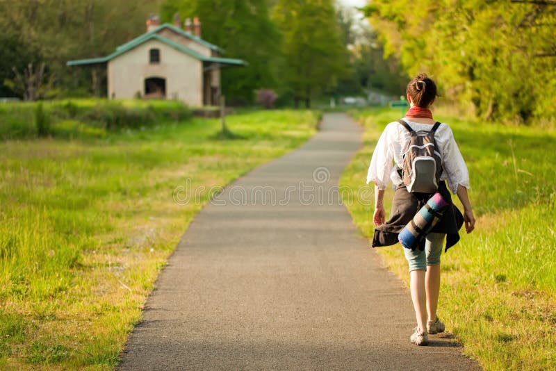 Back view of woman walking on country road at springtime in France. Back view of woman walking on country road at springtime in France