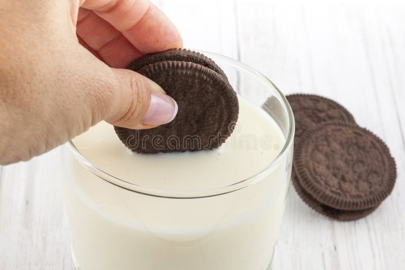 Vrouw die chocoladekoekjes in melk onderdompelen royalty-vrije stock afbeelding Vrouw die chocoladekoekjes in melk onderdompelen royalty-vrije stock afbeelding