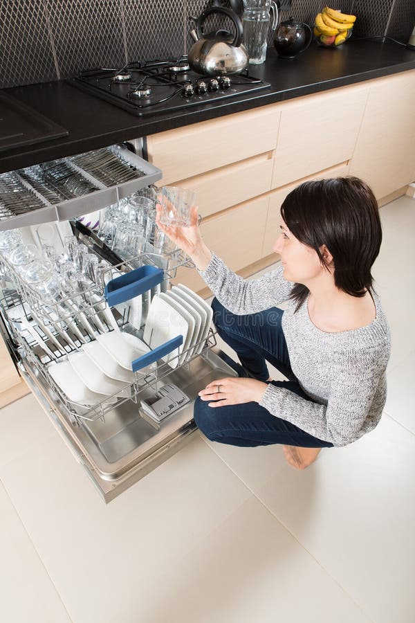 Vrouw die een afwasmachine in een moderne keuken met behulp van stock fotografie Vrouw die een afwasmachine in een moderne keuken met behulp van stock fotografie