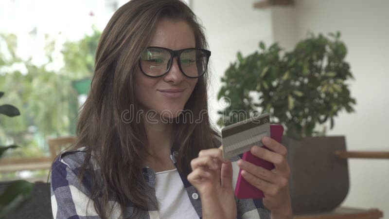 Vrouw die een creditcard houden en celtelefoon voor online het winkelen met behulp van stock video Vrouw die een creditcard houden en celtelefoon voor online het winkelen met behulp van stock video