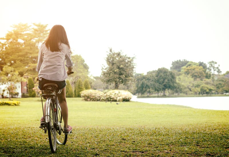 Vrouw die een fiets in een park openlucht bij de zomerdag berijden Actieve mensen Bevat gradiënt en het knippen masker