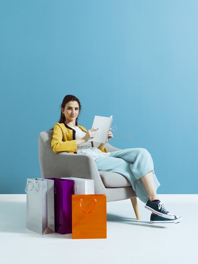 Vrouw die en een maniertijdschrift lezen winkelen royalty-vrije stock afbeeldingen Vrouw die en een maniertijdschrift lezen winkelen royalty-vrije stock afbeeldingen