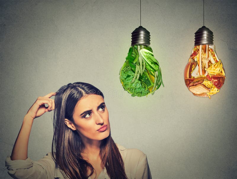 Vrouw die het bekijken omhoog ongezonde kost en groene die groenten denken als gloeilamp gestalte wordt gegeven royalty-vrije stock foto Vrouw die het bekijken omhoog ongezonde kost en groene die groenten denken als gloeilamp gestalte wordt gegeven royalty-vrije stock foto