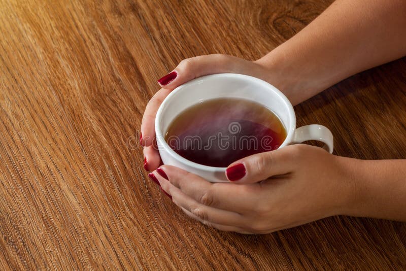 Vrouw die hete kop thee houden stock afbeelding Vrouw die hete kop thee houden stock afbeelding