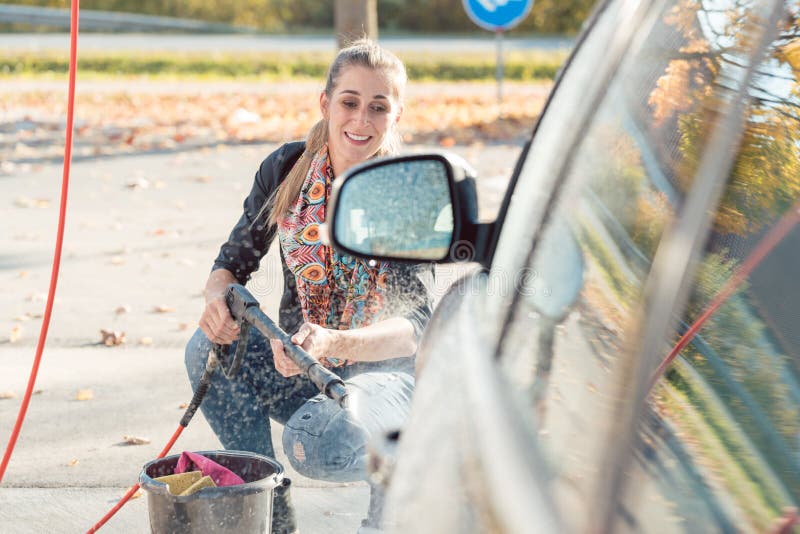 Vrouw die hoge drukpijp gebruiken om haar auto schoon te maken royalty-vrije stock afbeelding Vrouw die hoge drukpijp gebruiken om haar auto schoon te maken royalty-vrije stock afbeelding