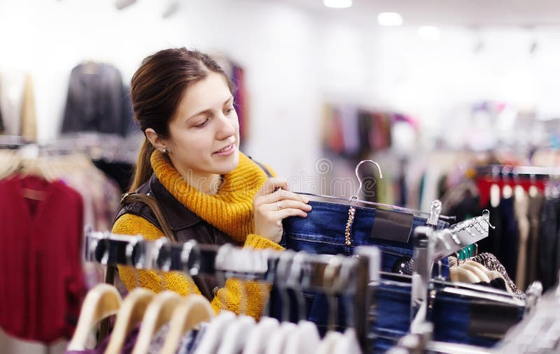Vrouw die jeans kiezen bij winkel royalty-vrije stock afbeeldingen Vrouw die jeans kiezen bij winkel royalty-vrije stock afbeeldingen
