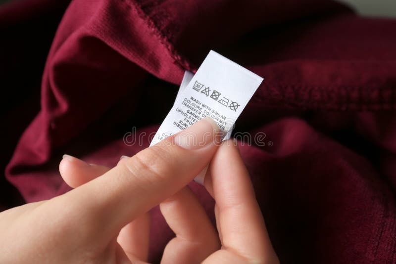 Vrouw die kledingetiket leest met instructies voor zorg op rode kleding