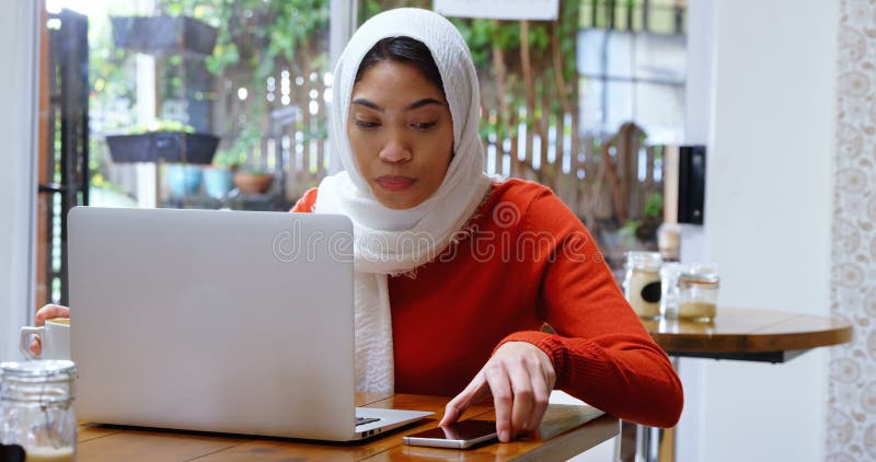 Vrouw die koffie terwijl het gebruiken van laptop en mobiele telefoon 4 dun gebruikt