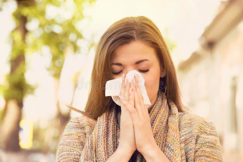 Vrouw die met allergiesymptomen neus blazen