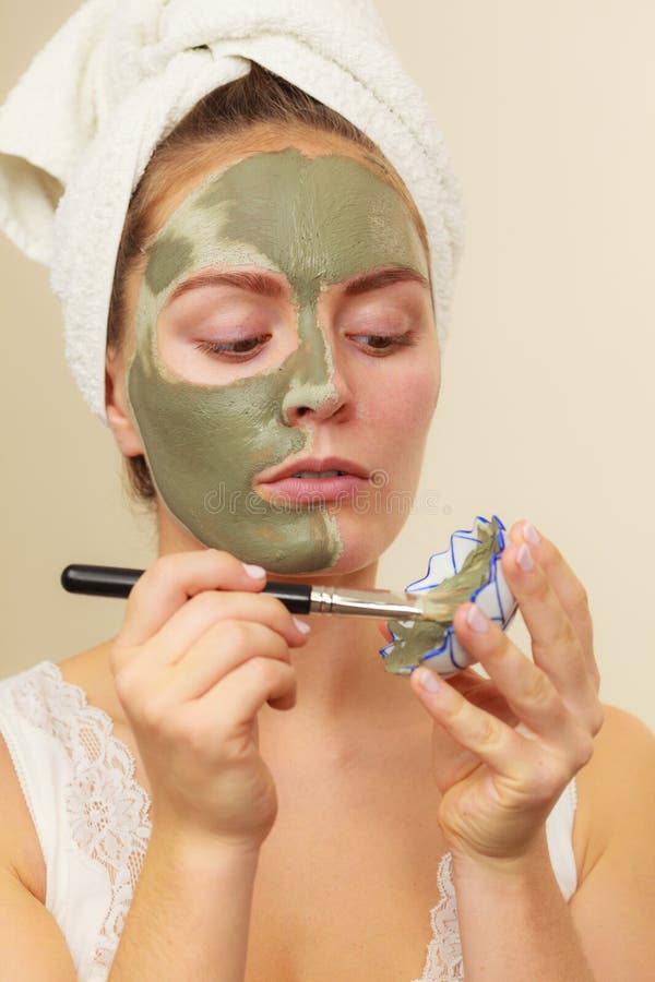 Vrouw die met de moddermasker van de borstelklei op haar gezicht van toepassing zijn stock afbeelding Vrouw die met de moddermasker van de borstelklei op haar gezicht van toepassing zijn stock afbeelding