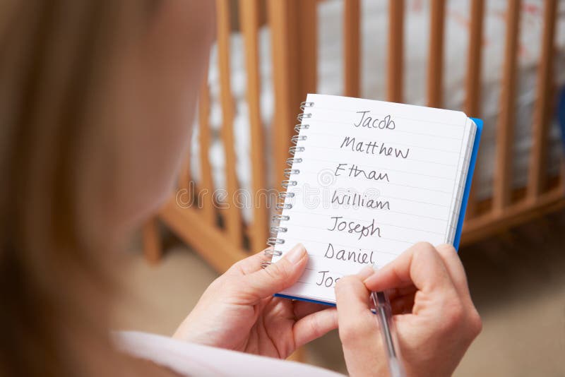 Close Up Of Woman Writing Possible Names For Baby Boy In Nursery. Close Up Of Woman Writing Possible Names For Baby Boy In Nursery