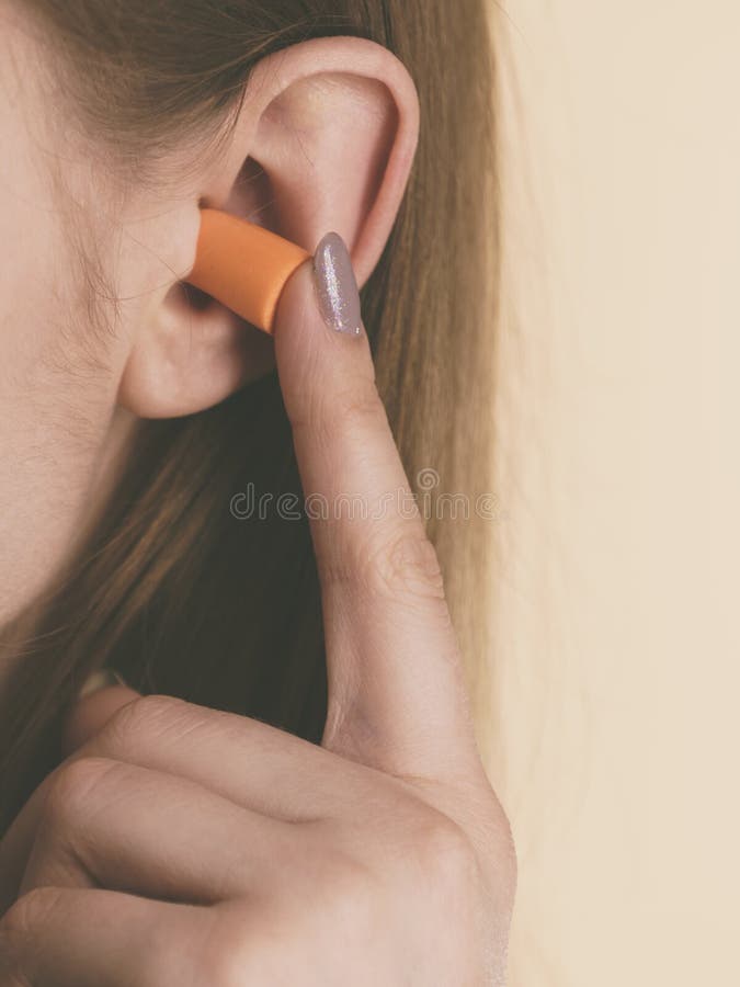 Vrouw die oorstoppen zetten in oren stock foto Vrouw die oorstoppen zetten in oren stock foto