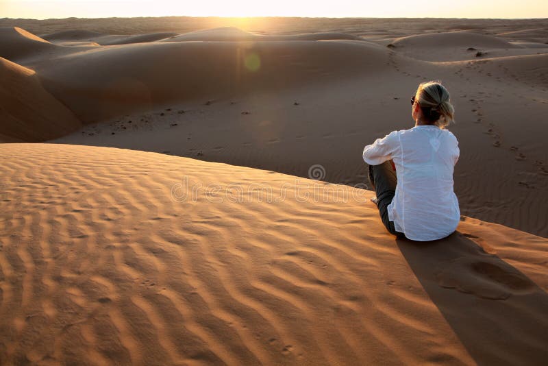 Vrouw die op de zonsondergang op de rode zandduinen letten van Oman royalty-vrije stock foto's Vrouw die op de zonsondergang op de rode zandduinen letten van Oman royalty-vrije stock foto's