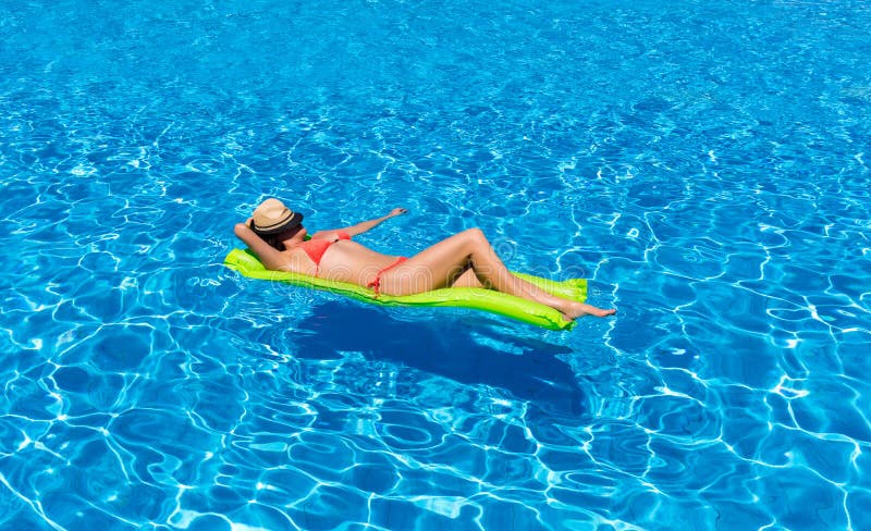 Vrouw die op een matras in een zwembad drijven stock afbeeldingen Vrouw die op een matras in een zwembad drijven stock afbeeldingen
