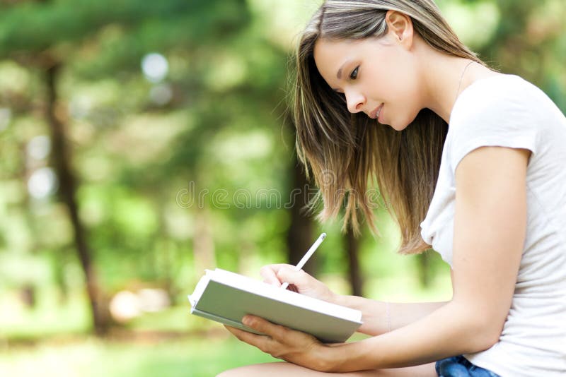 Vrouw die op haar agenda bij het park schrijven royalty-vrije stock foto Vrouw die op haar agenda bij het park schrijven royalty-vrije stock foto