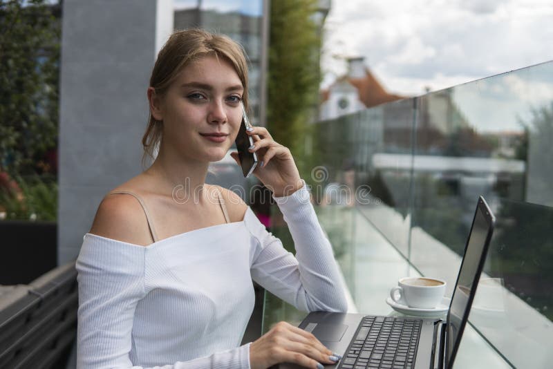 Vrouw die op kantoor aan laptop werkt terwijl het spreken telefoneert Portret van jonge lachende zakenvrouw die haar beste noemt royalty-vrije stock afbeelding Vrouw die op kantoor aan laptop werkt terwijl het spreken telefoneert Portret van jonge lachende zakenvrouw die haar beste noemt royalty-vrije stock afbeelding