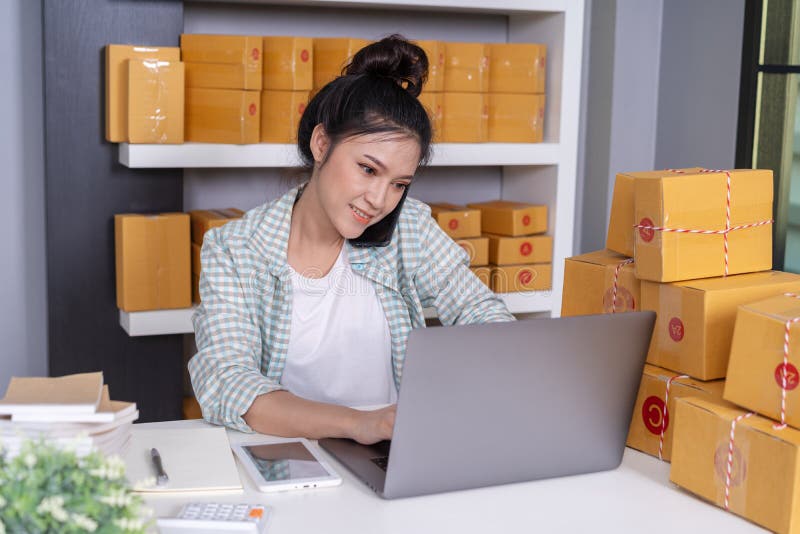 Vrouw die op smartphone en gebruikscomputerlaptop aan online het verkopen van product van huisbureau spreken stock afbeelding Vrouw die op smartphone en gebruikscomputerlaptop aan online het verkopen van product van huisbureau spreken stock afbeelding
