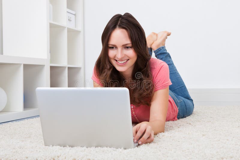 Vrouw die op vloer voor laptop liggen