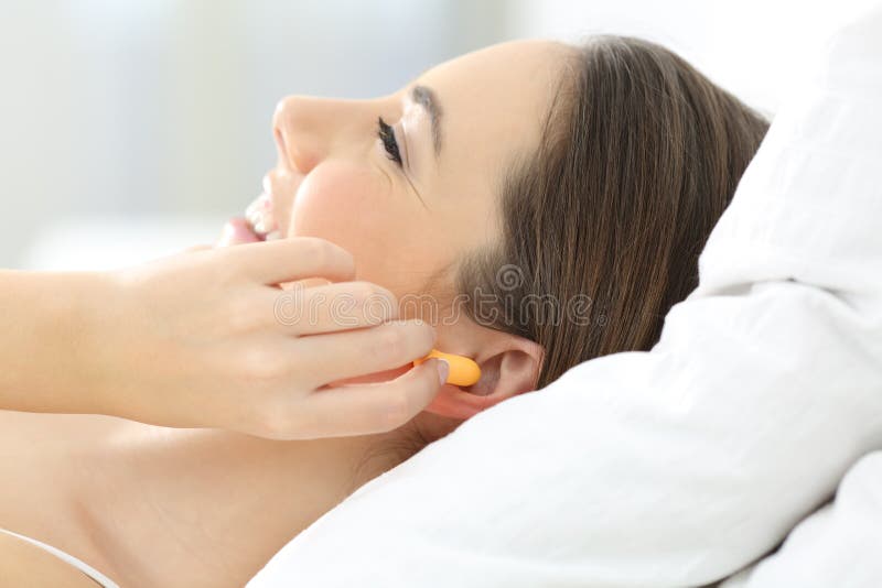 Vrouw die oren behandelen die stoppen op het bed gebruiken stock foto Vrouw die oren behandelen die stoppen op het bed gebruiken stock foto