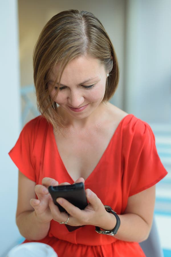 Vrouw die in rode kledingszitting in koffie beneden en Internet die in smartphone surfen kijken royalty-vrije stock afbeeldingen Vrouw die in rode kledingszitting in koffie beneden en Internet die in smartphone surfen kijken royalty-vrije stock afbeeldingen
