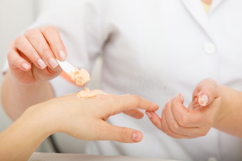 Vrouw die room op hand toepassen die spatel gebruiken stock fotografie Vrouw die room op hand toepassen die spatel gebruiken stock fotografie