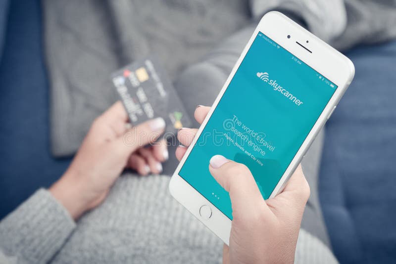 Vrouw die de Skyscanner-app gebruikt op een Apple iPhone 8 Plus stock afbeelding