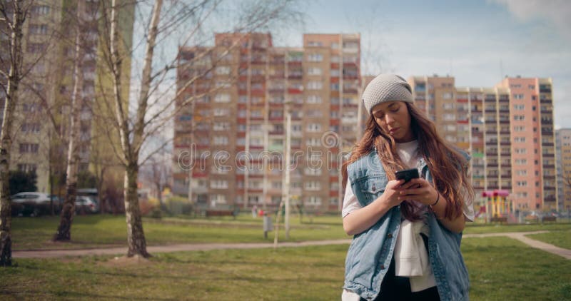 Vrouw die smartphone gebruikt voor het doorbladeren van sociale media die buitenshuis sms'en