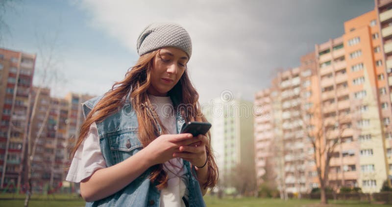 Vrouw die smartphone gebruikt voor het doorbladeren van sociale media die buitenshuis sms'en