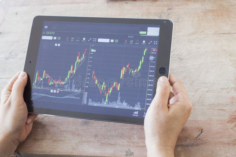 Vrouw die tablet voor de voorraad van de aantalhandelaar en verslag op notitieboekje kijken stock foto's Vrouw die tablet voor de voorraad van de aantalhandelaar en verslag op notitieboekje kijken stock foto's