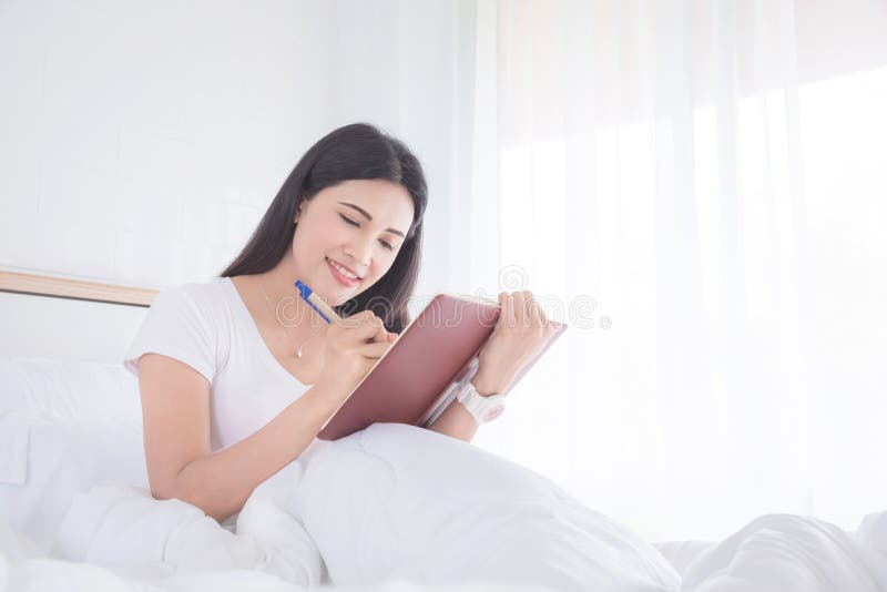 Vrouw die terwijl het schrijven van agenda op notitieboekje glimlachen stock foto's Vrouw die terwijl het schrijven van agenda op notitieboekje glimlachen stock foto's