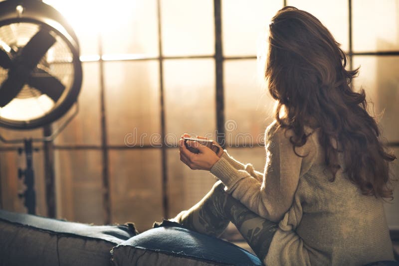 Vrouw die van kop van drank in zolderflat genieten royalty-vrije stock foto Vrouw die van kop van drank in zolderflat genieten royalty-vrije stock foto